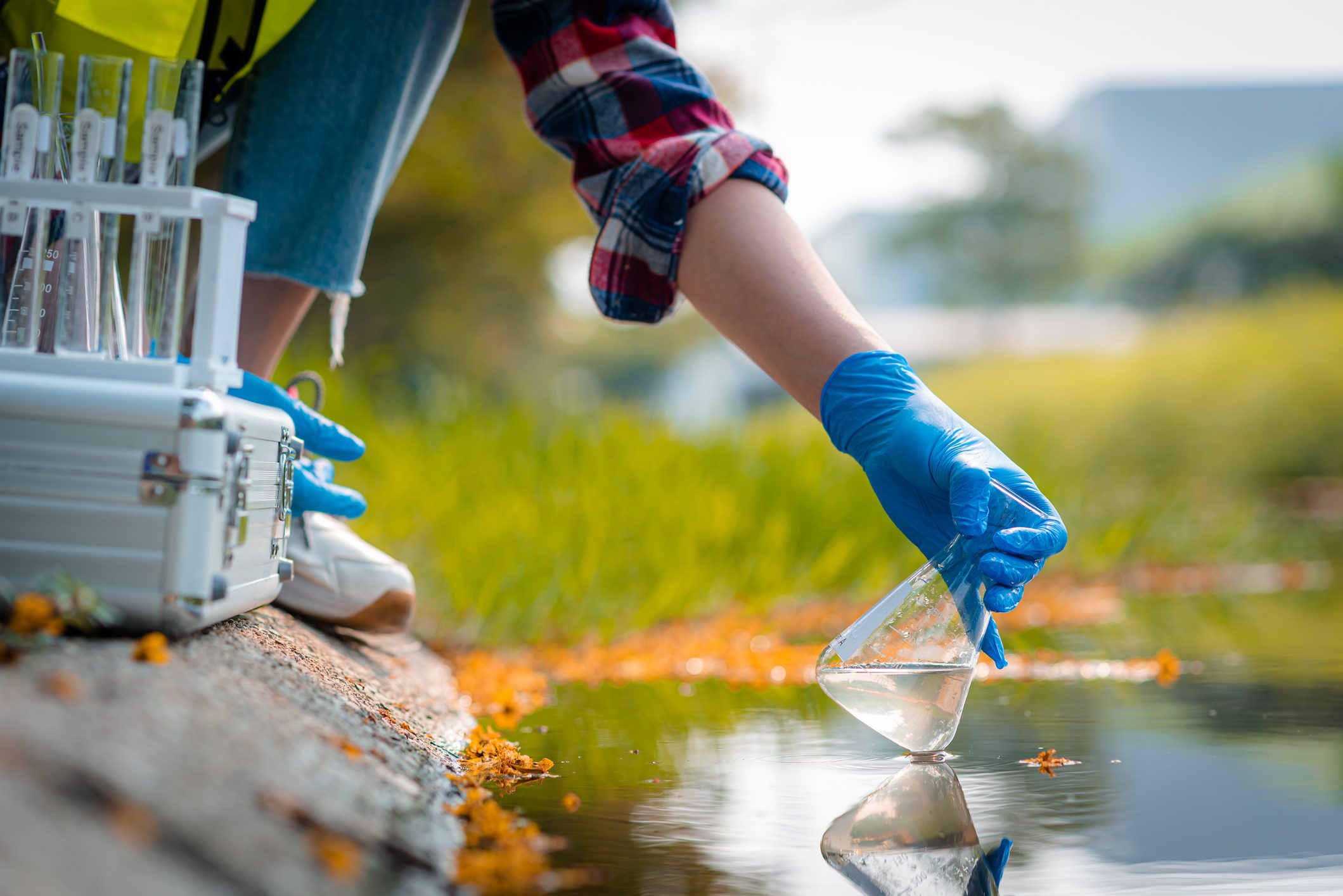 Hands of scientists collecting water samples for analysis and research on water quality.